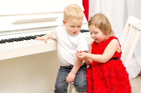 Pojke med flicka sitter nära vit piano — Stockfoto