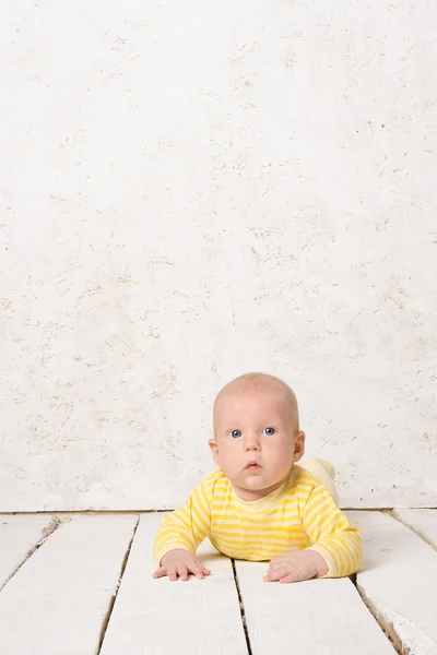 Chlapec na dřevěné podlaze bílé — Stock fotografie