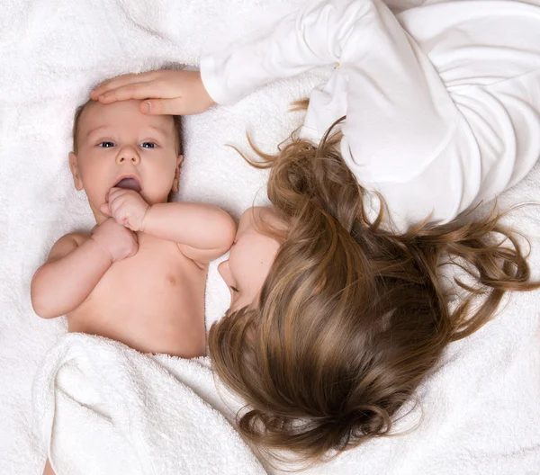 Schwester und ihr neugeborener Bruder liegen im Bett — Stockfoto