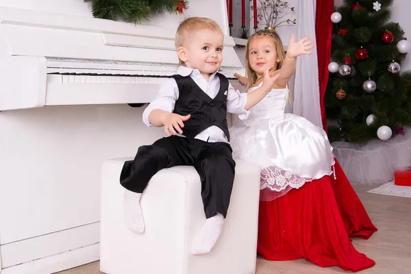 Chłopiec i dziewczynka siedzi w pobliżu biały fortepian — Zdjęcie stockowe