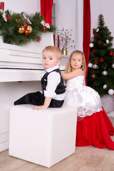 Chlapec a dívka sedící poblíž bílý klavír — Stock fotografie