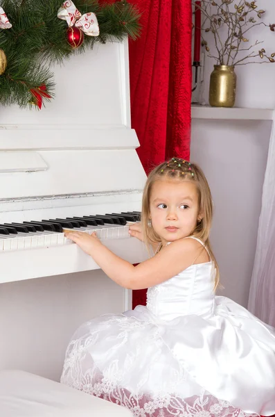 Chica jugando en blanco piano — Foto de Stock