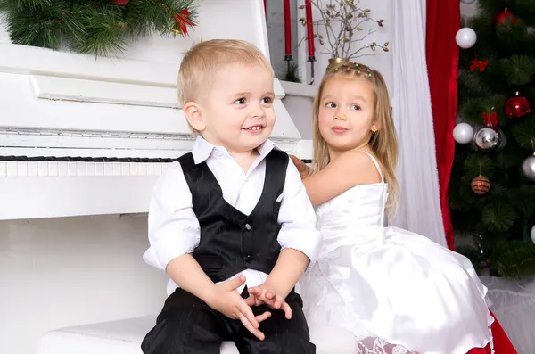 Menino e menina sentados perto de piano branco — Fotografia de Stock