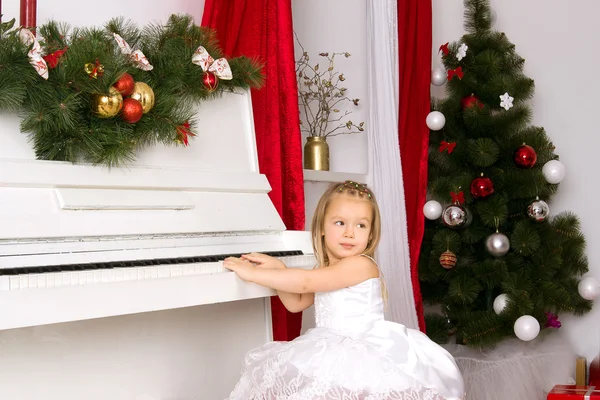 Flicka som leker på vit piano — Stockfoto