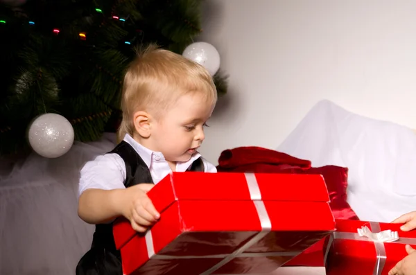 Jongen uitpakken cadeaus onder de kerstboom — Stockfoto