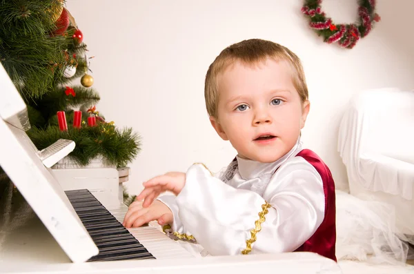 Pojke spela piano på tröskeln till jul — Stockfoto