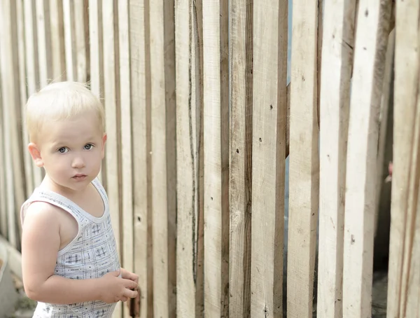 Jongen op achtergrond van houten hek — Stockfoto