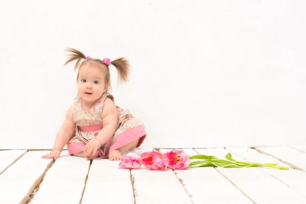 Meisje van de baby in roze jurk met bloemen — Stockfoto