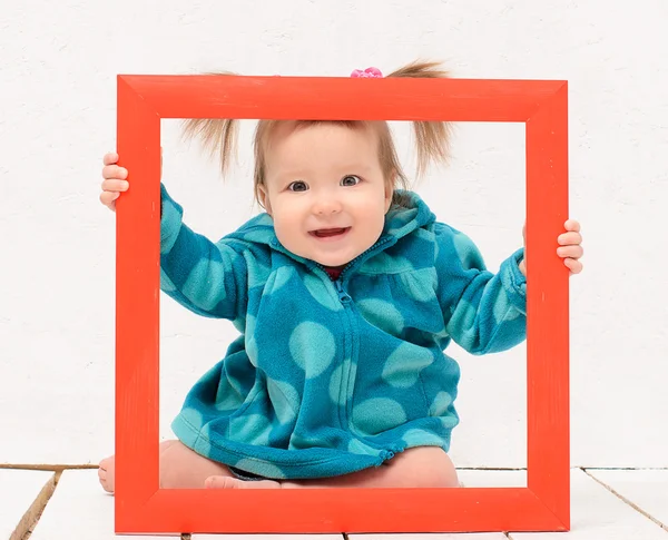 Baby girl holding hands red frame — Stock Photo, Image