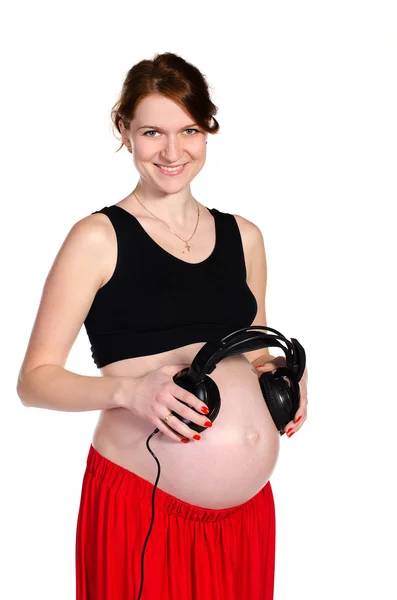 Беременная с наушниками возле живота — стоковое фото