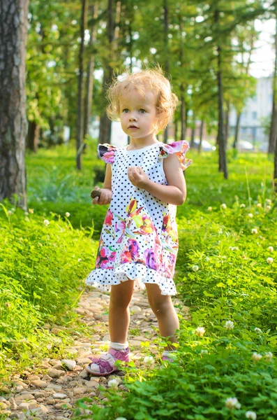 Liten blond flicka vandrar i parken — Stockfoto