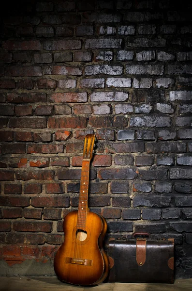 Kytara a retro tašku na cihlovou zeď pozadí — Stock fotografie