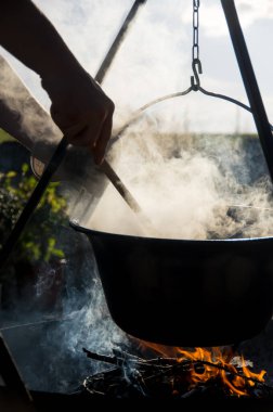 Kamp ateşinin üzerinde buharlı çaydanlık, ateş kasesinin üstünde çaydanlık.