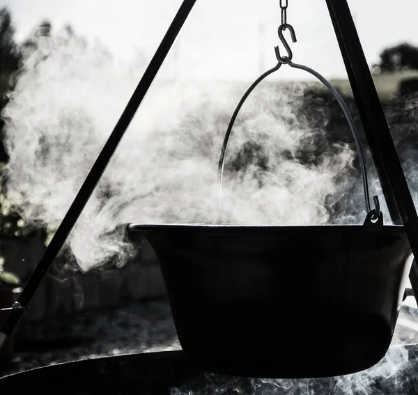 Kamp ateşinin üzerinde buharlı çaydanlık, ateş kasesinin üstünde çaydanlık.