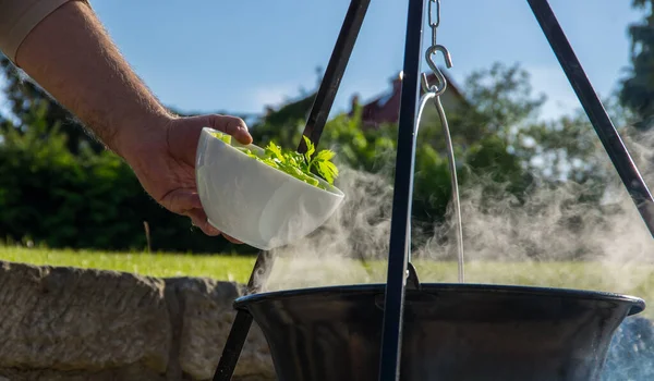 Kamp ateşinin üzerinde buharlı çaydanlık, ateş kasesinin üstünde çaydanlık.