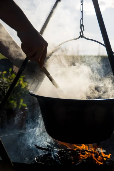 Kamp ateşinin üzerinde buharlı çaydanlık, ateş kasesinin üstünde çaydanlık.