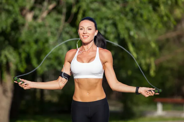 A sportive beautiful woman in a park with a rope — Stock Photo, Image