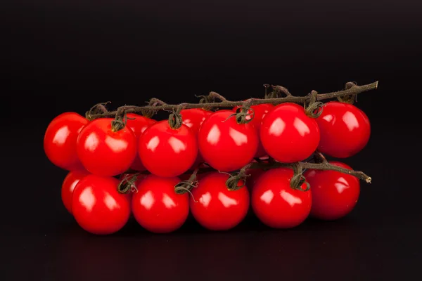 Ramita de tomates cherry aislados sobre un fondo negro — Foto de Stock