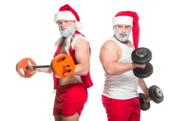 Navidad. Retrato de dos fuertes atletas barbudos musculosos disfrazados de Santa Claus, entrenando levantando barras aisladas sobre fondo blanco — Foto de Stock