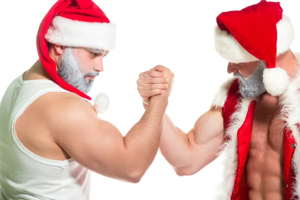 Navidad. Retrato de cerca de dos serias Santa Claus musculosas confiadas que realizan técnicas de lucha libre de brazos aisladas sobre fondo blanco — Foto de Stock