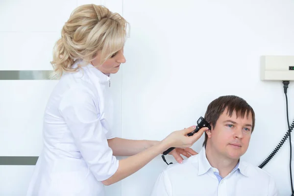 Un otorrinolaringólogo examina el canal auditivo externo de un paciente masculino con otoscopio en el hospital — Foto de Stock