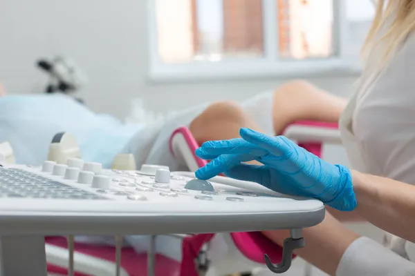 Ginekolog wykonuje ultradźwiękową diagnostykę dla dziewczyny leżącej na krześle ginekologicznym. Zarządzanie ciążą, monitorowanie stanu zdrowia płodu — Zdjęcie stockowe