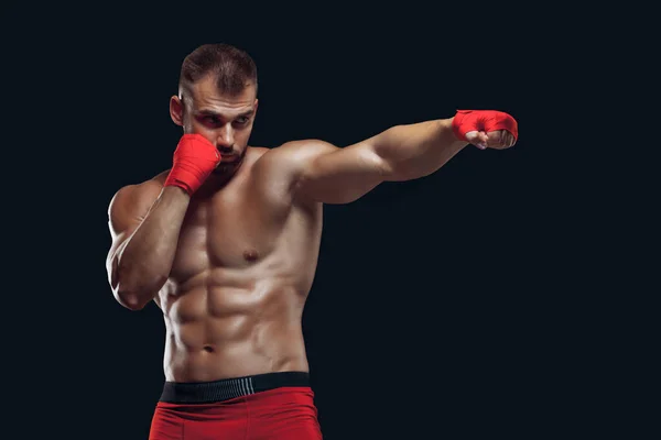 Vista frontal de un deportista con guantes de boxeo practicando técnicas de lucha aisladas sobre fondo negro —  Fotos de Stock
