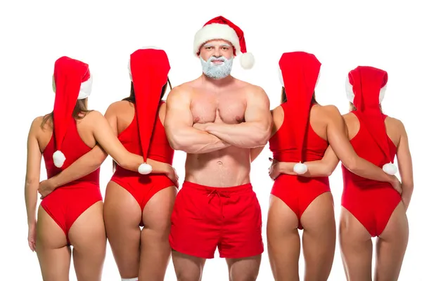 Silny muskularny siwobrody Święty Mikołaj z nagim tułowia i idealny sexy blondynka i brunetka dziewczyny pozowanie w bieliźnie i Santa Claus kapelusz na zawartość Bożego Narodzenia, izolowany na białym tle — Zdjęcie stockowe