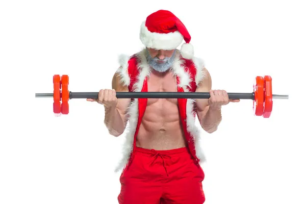Різдво. Сильний м'язовий Санта Клаус з сірою бородою у кришталевому капелюсі, а червоні шорти піднімають важкий дзвін у спортзалі, виконуючи тренування, ізольовані на білому тлі.. — стокове фото
