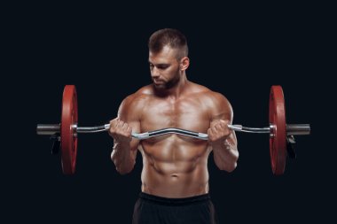 Siyah arka planda izole edilmiş halterle egzersiz yapan güçlü bir vücut geliştiricinin ön görüntüsü.