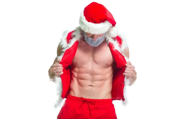 Natale. Ritratto di atleta muscoloso sexy forte in costume da Babbo Natale con barba grigia in posa mostrando i suoi addominali isolati su sfondo bianco — Foto Stock