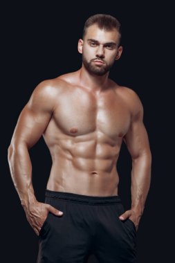 Siyah arka planda izole edilmiş kaslı ve formda genç vücut geliştirici fitness erkek modeli
