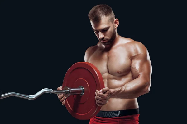 Vista lateral de un atleta masculino colocando un disco sobre una barra aislada sobre fondo negro — Foto de Stock