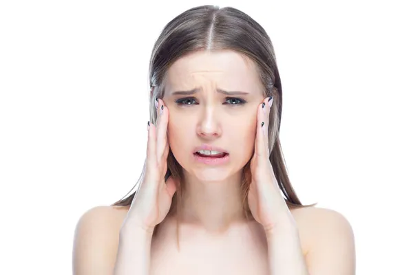Foto de uma jovem menina chorando bonita experimentando um ataque de dor de cabeça grave, de pé com as mãos perto de sua cabeça em um fundo branco — Fotografia de Stock