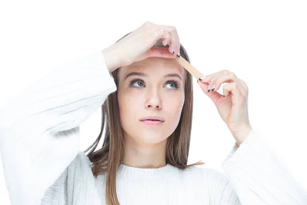 Nahaufnahme einer jungen, traurigen Frau, die nach einer auf weißem Hintergrund isolierten Verletzung einen Klebeverband auf die Stirn legt — Stockfoto