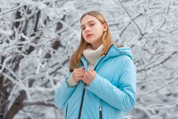 Portret troskliwej miłej dziewczyny stojącej zimą w śnieżnym parku na tle zamarzniętych drzew na Boże Narodzenie — Zdjęcie stockowe