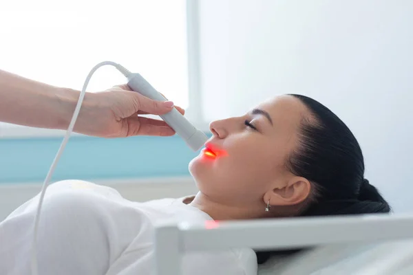 El uso de un dispositivo láser terapéutico por un dermatólogo durante un procedimiento de rejuvenecimiento cosmético en la clínica — Foto de Stock