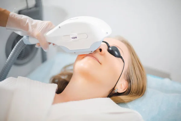 Zbliżenie twarzy młodej kobiety, podczas gdy kosmetolog wykonuje zabieg laserowego usuwania niechcianych włosów twarzy i górnej wargi w salonie piękności — Zdjęcie stockowe