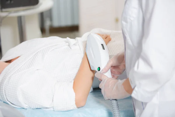 Nahaufnahme Laser-Haarentfernung am Arm eines jungen Mädchens durch einen professionellen Spezialisten in einem modernen Kosmetikbüro — Stockfoto