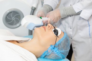 Güzellik salonundaki kadın müşteri, renklendirici bir fotoğraf yenileme işleminden geçiyor. Pigmentasyon izleri siliniyor. Kendi kolajeni üreterek gençleştirme sürecini başlatılıyor