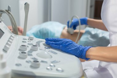 Doktor randevusu sırasında hamile kadının karnına ultrason sondası yerleştirirken çekilmiş fotoğraf.