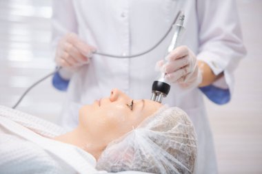 Modern bir güzellik salonunda RF kaldırma işlemi sırasında rahatlayan güzel bir kadının portresini yakından çek.