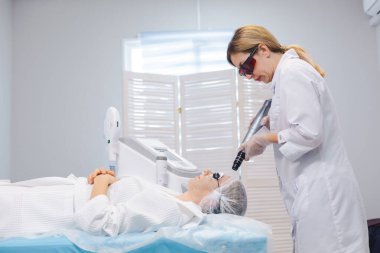 Bir güzellik salonunda karbon soyma işlemi sırasında koruyucu gözlük takan genç bir kızın yan görüntüsü.