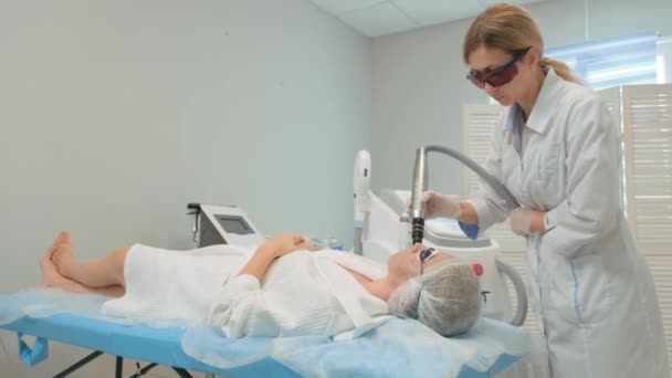 Cosmetologische procedure. Vrouw met een beschermende bril tijdens een carbon peeling procedure in een schoonheidssalon — Stockvideo