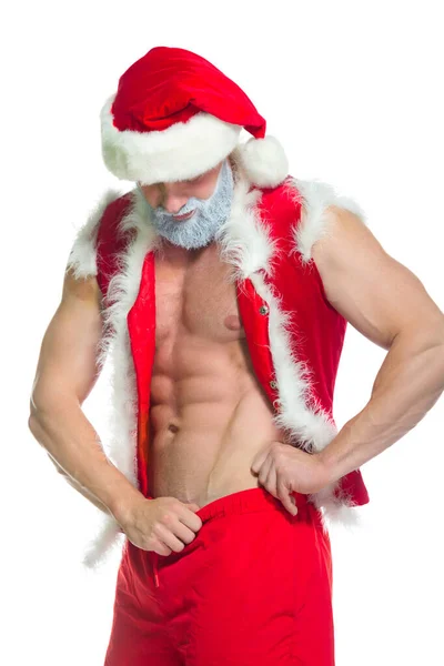 Natale. Ritratto di atleta muscoloso sexy forte in costume da Babbo Natale con barba grigia in posa mostrando i suoi addominali isolati su sfondo bianco — Foto Stock