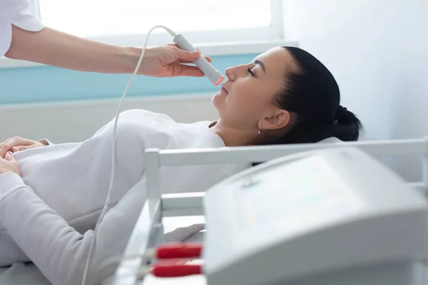 O uso de um dispositivo terapêutico a laser por um dermatologista durante um procedimento de rejuvenescimento cosmético na clínica — Fotografia de Stock