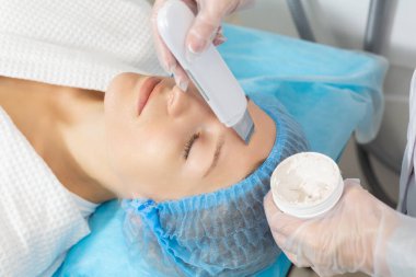 Profesyonel bir kozmetik uzmanı tarafından güzellik salonunda yapılan ultrasonik yüz temizleme. Derinin üst tabakasını nazikçe soyar, besin ve tıbbi ürünlerin daha iyi nüfuz etmesini sağlar.