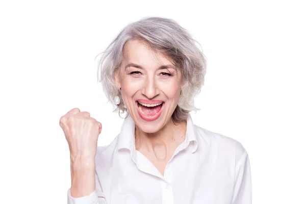 Porträt einer fröhlichen, fröhlichen Seniorin, die laut schreit und den Sieg mit erhobener Faust vor weißem Hintergrund gestikuliert — Stockfoto