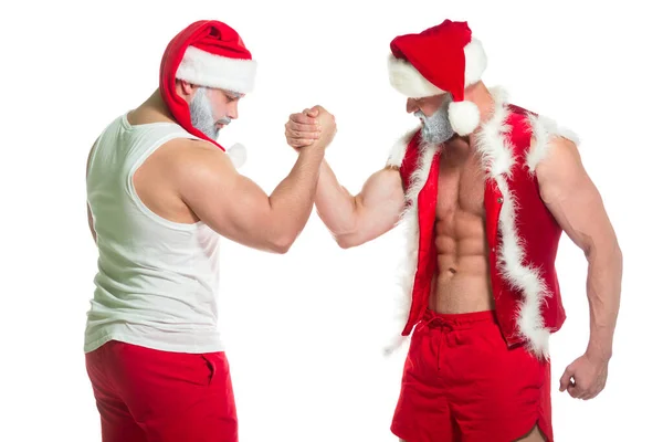 Święta. Portret dwóch silnie umięśnionych Mikołajów wykonujących techniki z siłowania na rękę odizolowanych na białym tle — Zdjęcie stockowe