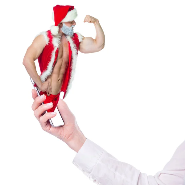 Navidad fitness en línea. Collage con Santa Claus muscular y smartphone en la mano. El atleta muestra los bíceps del brazo. Gimnasio online. Vacaciones. Descuentos. Aislado sobre fondo blanco — Foto de Stock